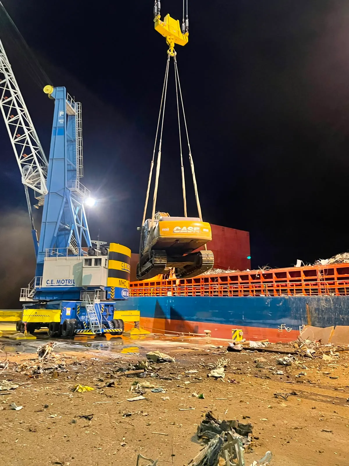 Grúa elevando maquinaria junto a un buque durante una operación nocturna